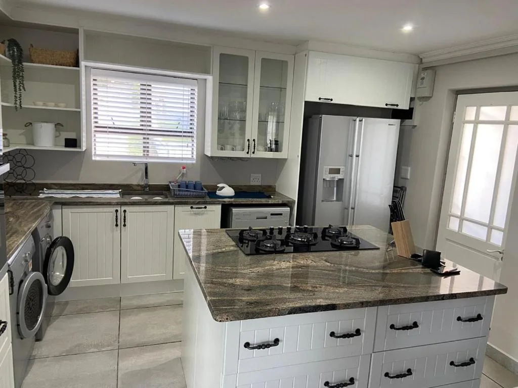 Modern kitchen with white cabinetry, granite island, and stainless steel appliances