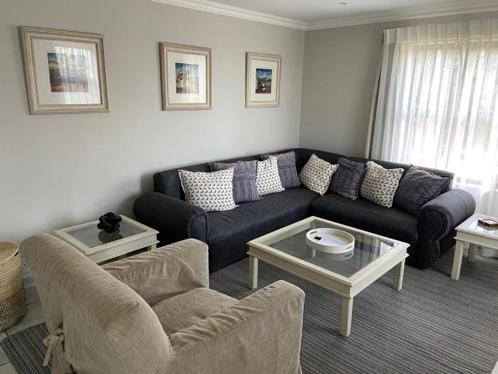 Spacious lounge with dark corner sofa, cream armchair, and coffee table