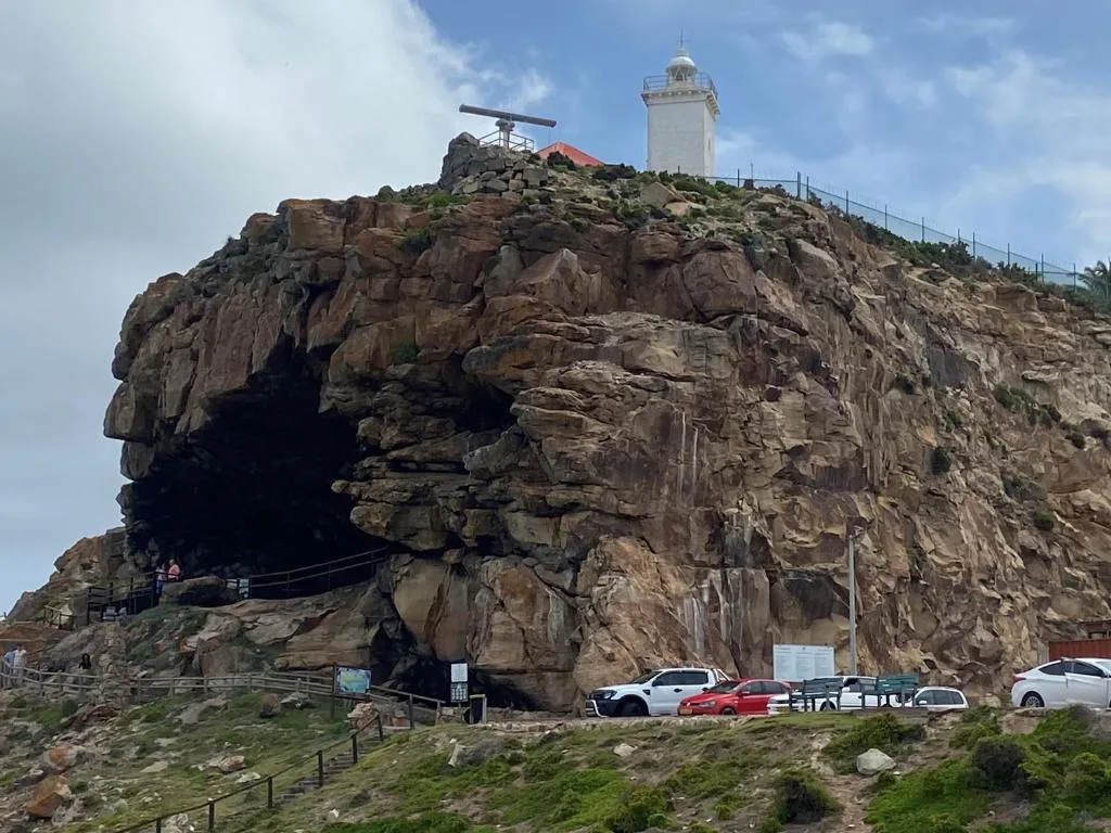 Iconic rocky headland with lighthouse and cave entrance landmark