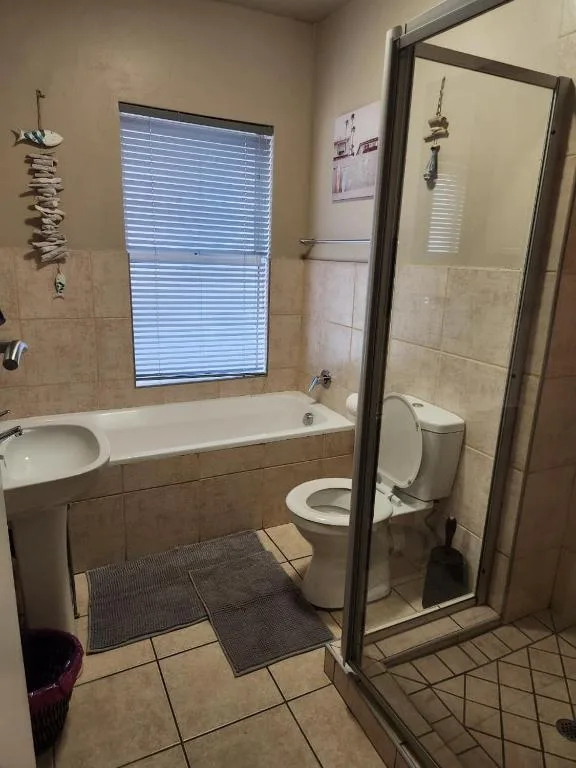 Bathroom with bathtub, toilet, sink, and shower enclosure with window