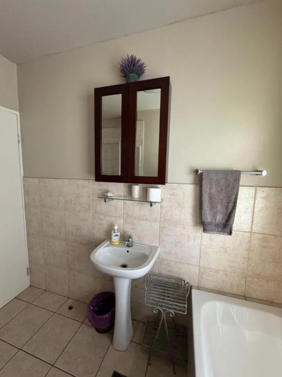 Bathroom with pedestal sink, mirror cabinet, and bathtub fixtures