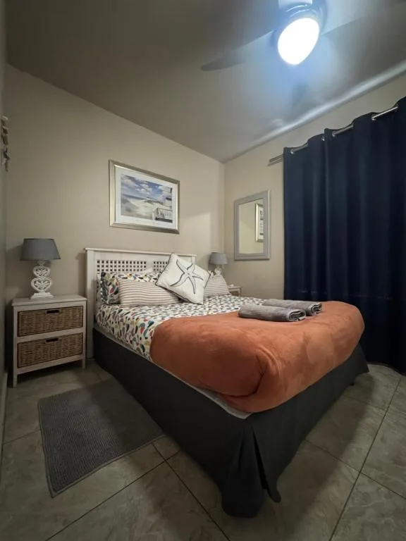 Cozy bedroom with queen bed, neutral bedding, and ceiling fan light