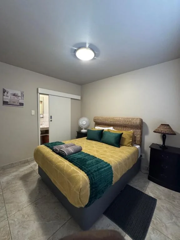 Bright bedroom with yellow bedding, wicker headboard, and green accents