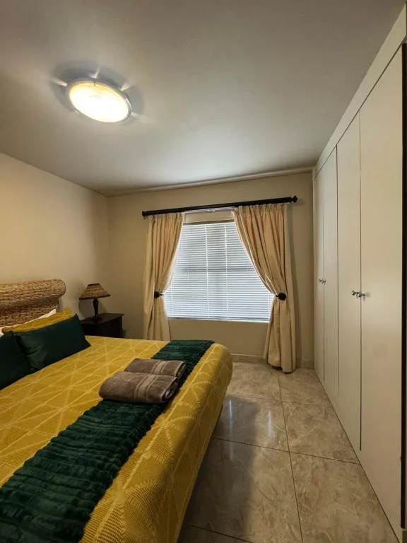 Bright bedroom with yellow bedding, green accents, and large window