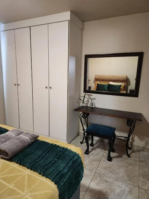 Bedroom with white wardrobe, mirror, desk, and yellow bedding