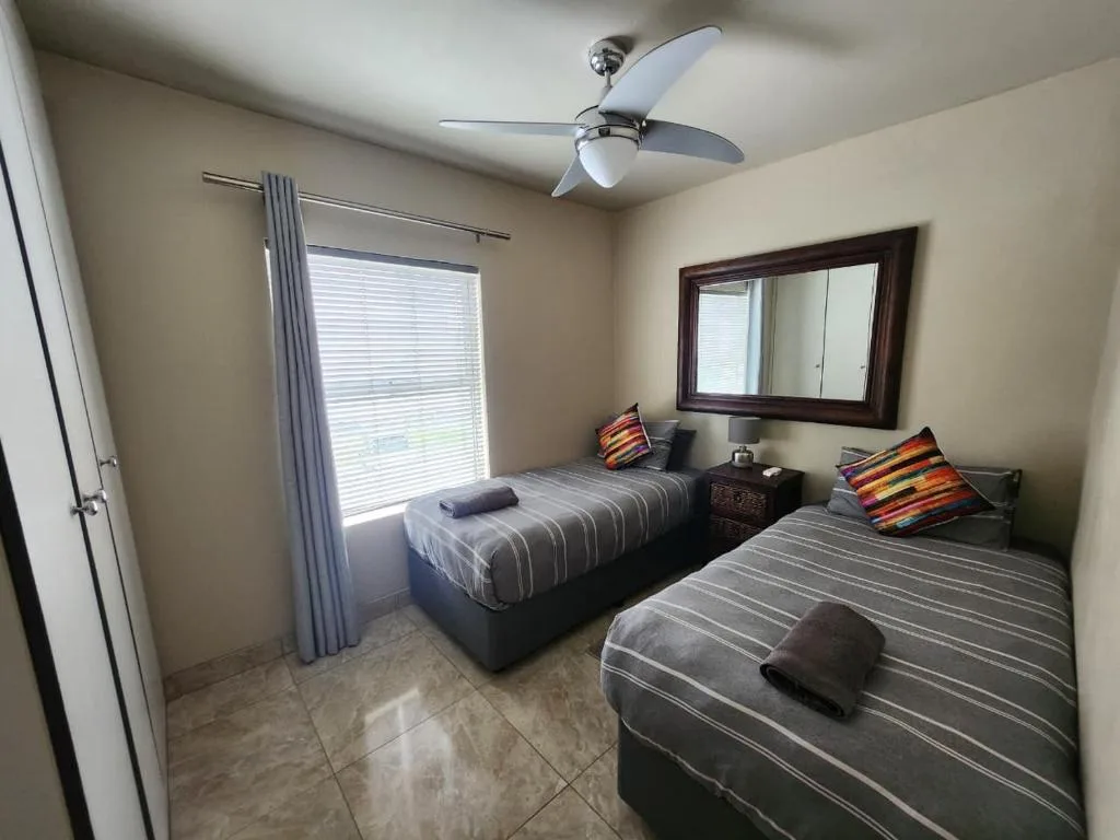 Twin bedroom with striped bedding, colorful pillows, and ceiling fan