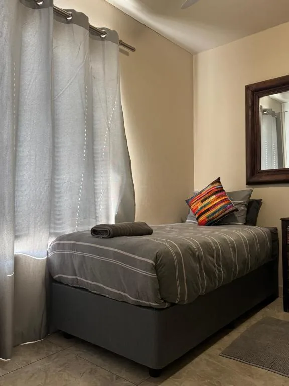Comfortable bedroom with striped bedding and colorful accent pillow