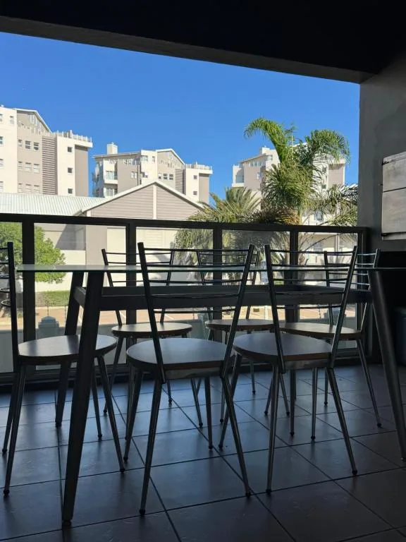 Modern patio with black dining furniture overlooking apartment buildings and palm trees