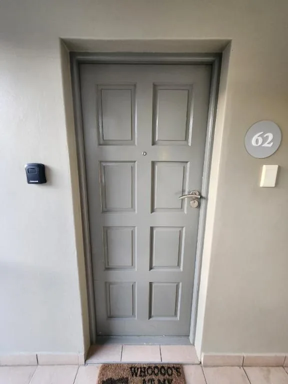 Entrance door to unit 62 with gray panel door and welcome mat