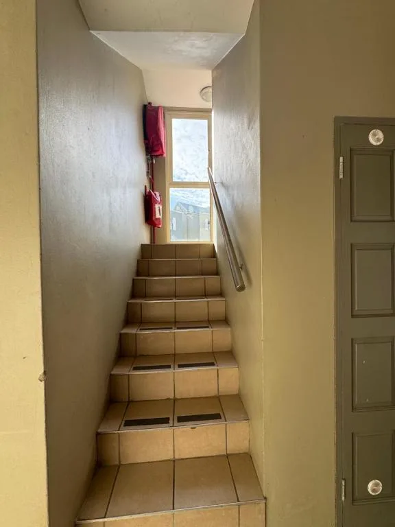 Interior staircase with terracotta tiles and metal railing, leading upwards
