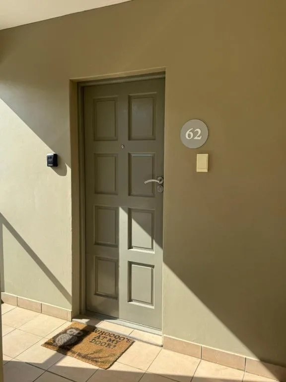 Unit 62 entrance door with welcome mat and apartment number plaque