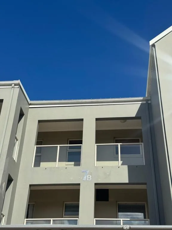 Modern cream-colored apartment building facade with balconies against blue sky