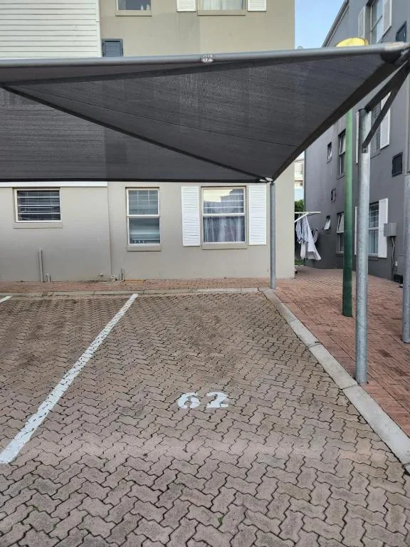 Beige apartment building with black shade awning and brick paved courtyard