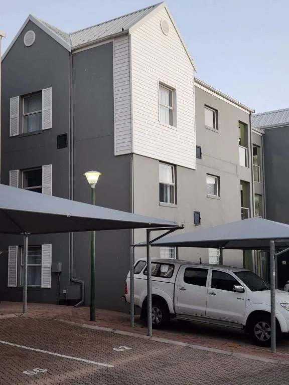 Modern multi-story building facade with carport and parked vehicle