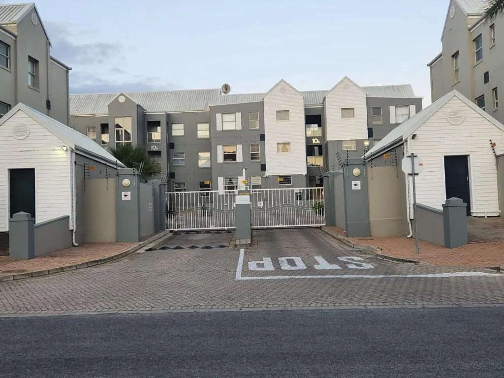 Modern gated apartment complex entrance with brick paving and contemporary buildings
