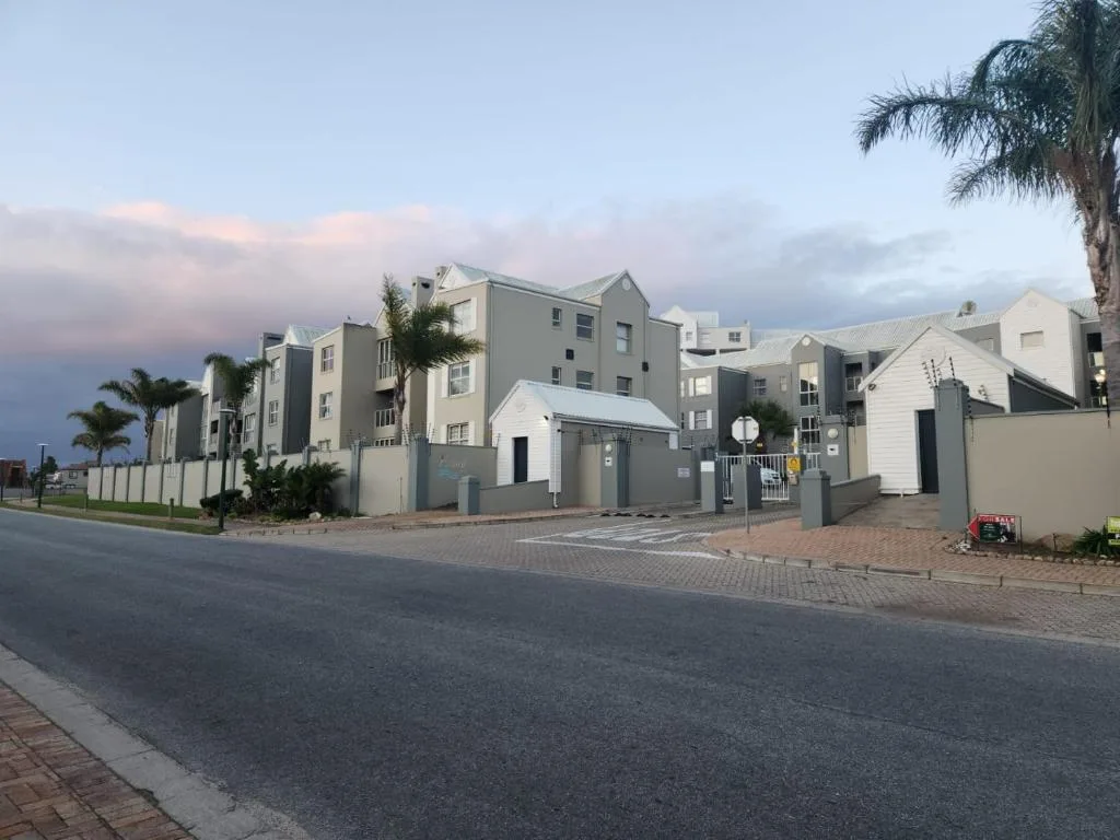 Modern apartment complex with gated entrance and palm trees at dusk