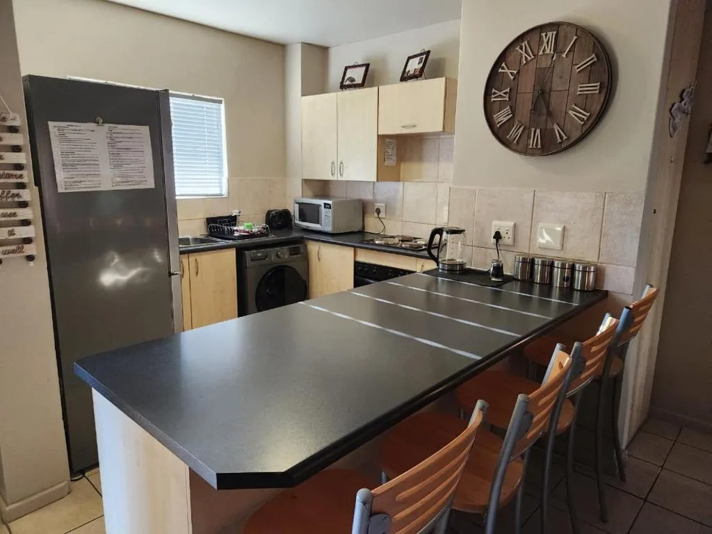 Modern kitchen with island counter, stove, refrigerator, and dining seating