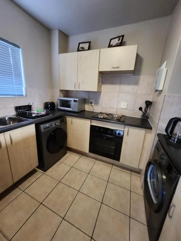 Modern kitchen with cream cabinetry, black appliances, and tiled flooring