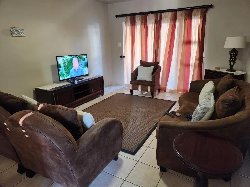 Spacious living room with brown sofas, TV, and striped red curtains