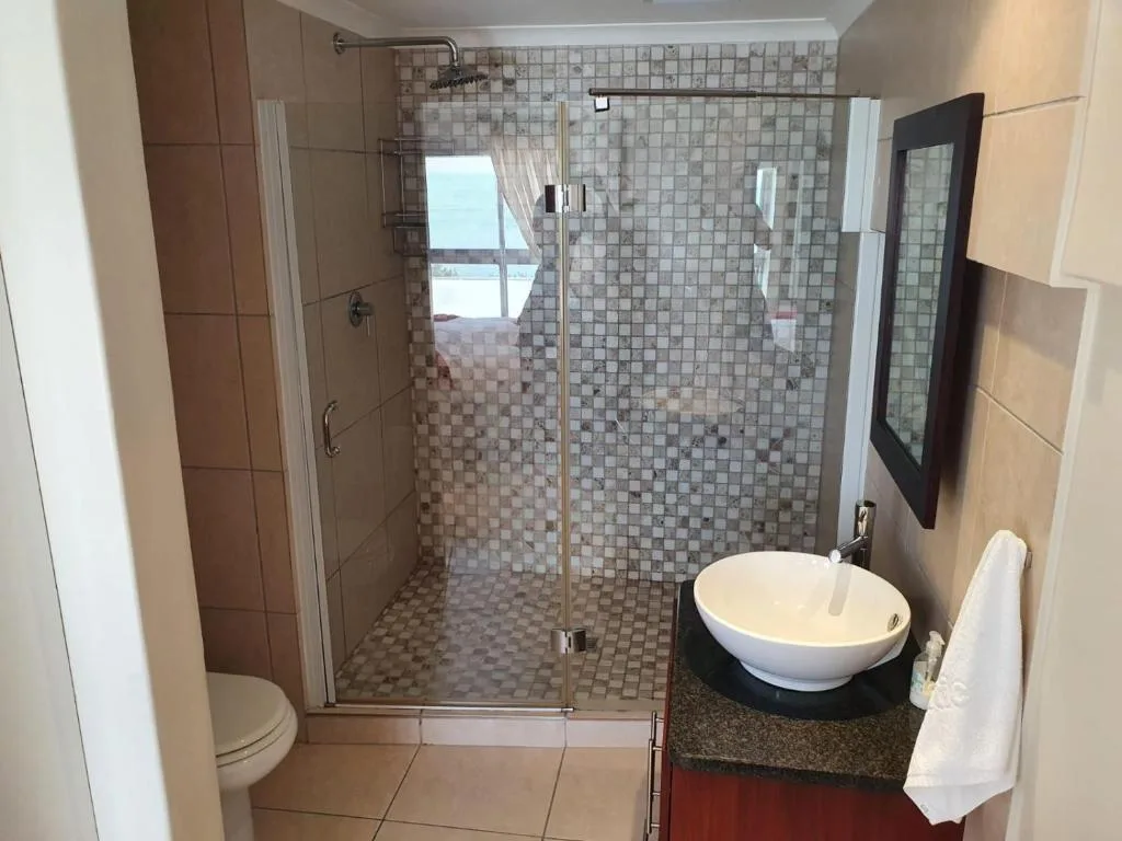 Modern bathroom with glass shower enclosure, round sink vanity, and tiled walls