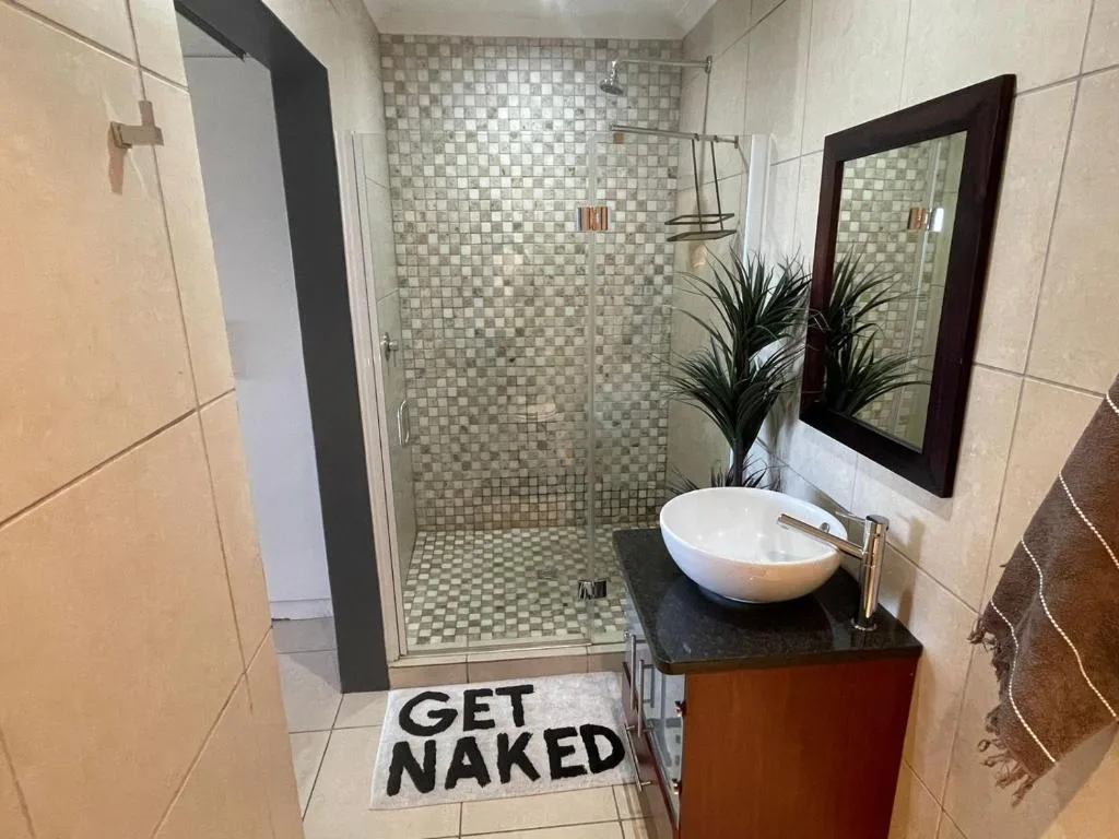 Modern bathroom with walk-in shower, vanity sink, and framed mirror