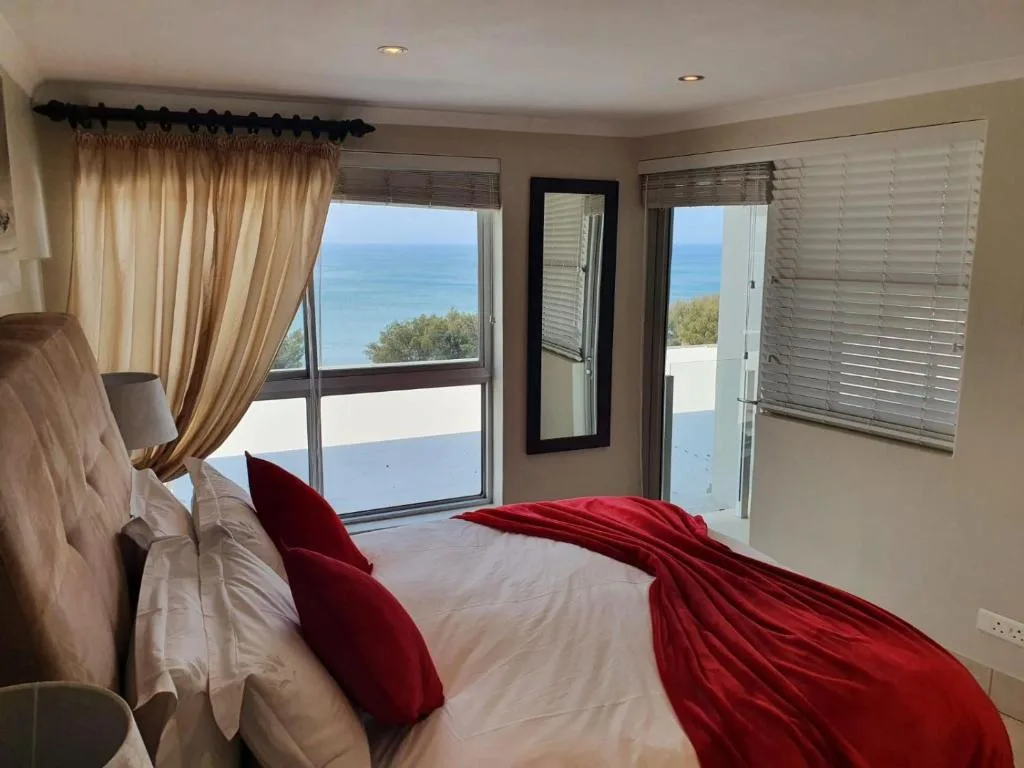 Bedroom with sea view through glass doors and windows overlooking ocean