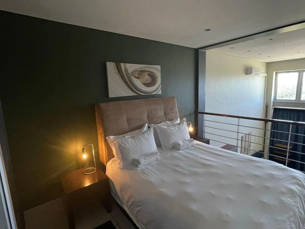 Modern bedroom with queen bed, gray headboard, and warm lighting