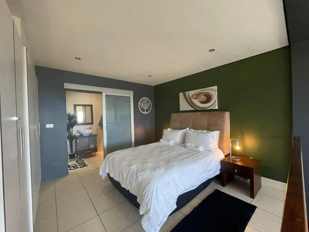 Spacious bedroom with queen bed, green accent wall, ensuite bathroom access