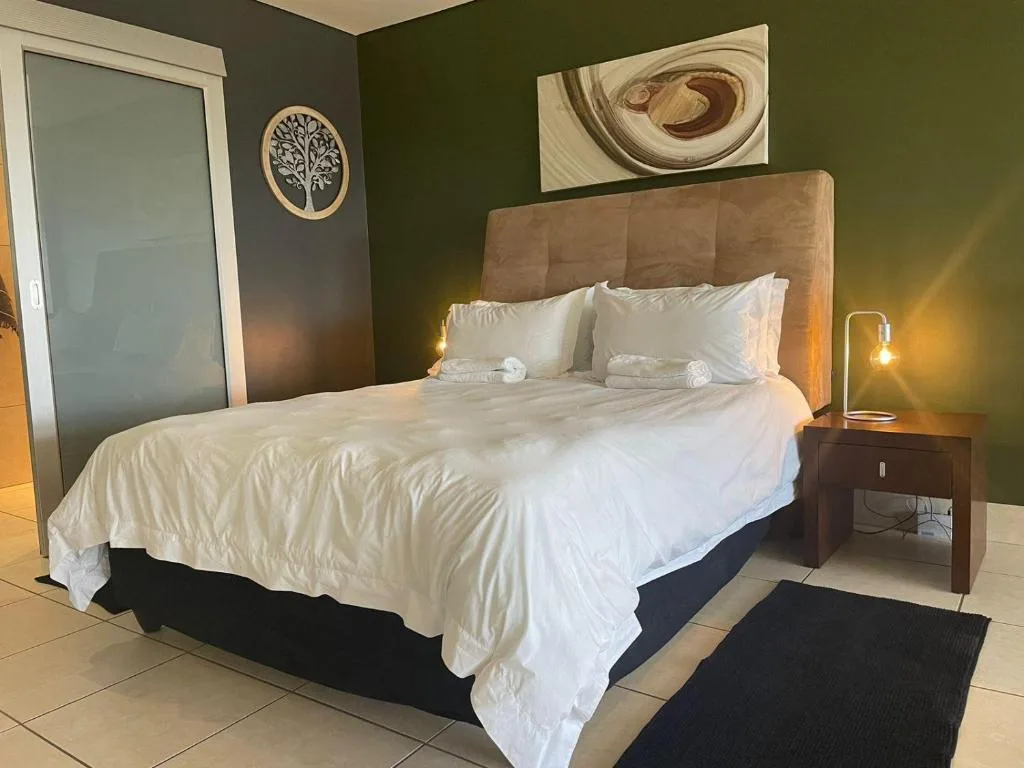 Modern bedroom with queen bed, olive walls, and contemporary artwork