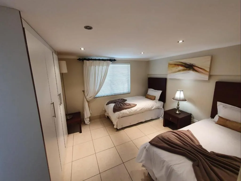 Spacious bedroom with three beds, dark wood headboards, and natural light
