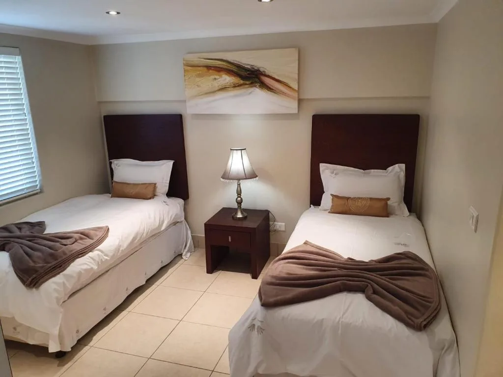 Twin bedroom with dark headboards, white linens, and bedside lamp
