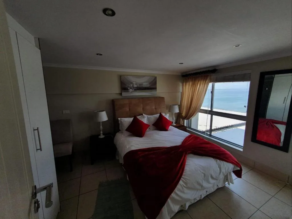 Bedroom with ocean view through large windows and red accent decor