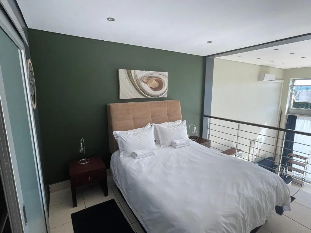 Modern bedroom with queen bed, green accent wall, and contemporary decor