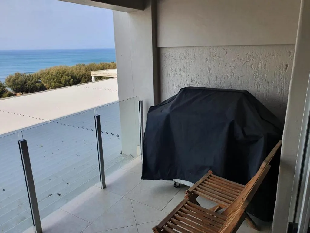 Oceanview balcony with covered grill and glass railing overlooking coast
