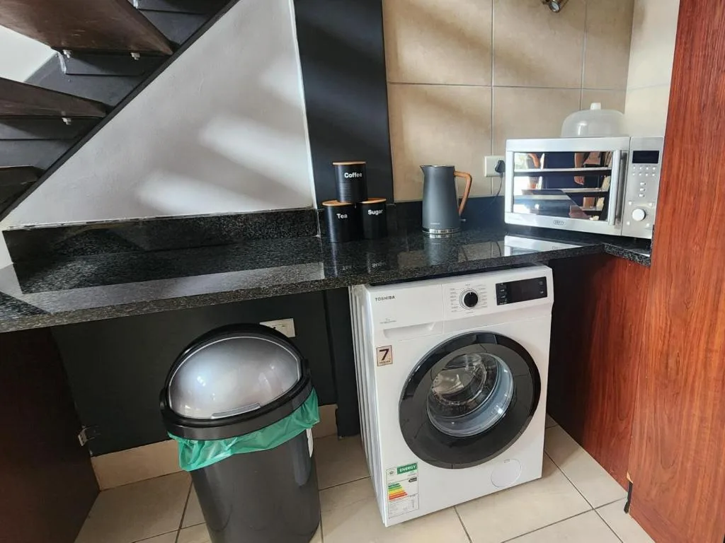 Modern kitchen with washing machine, microwave, and granite countertops