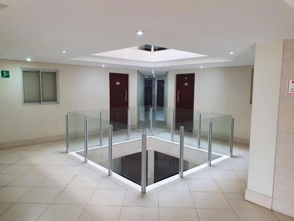 Modern interior hallway with glass railings and recessed ceiling lighting
