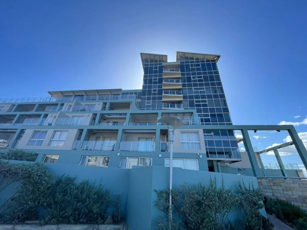 Modern multi-story blue apartment building facade under clear sky