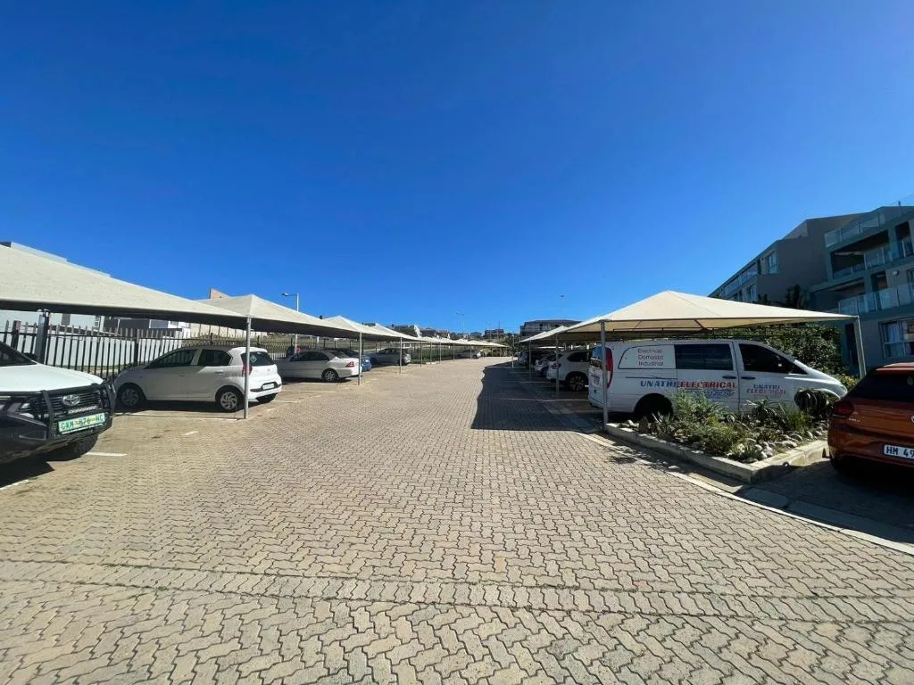 Paved driveway with parking spaces and cream shade structures