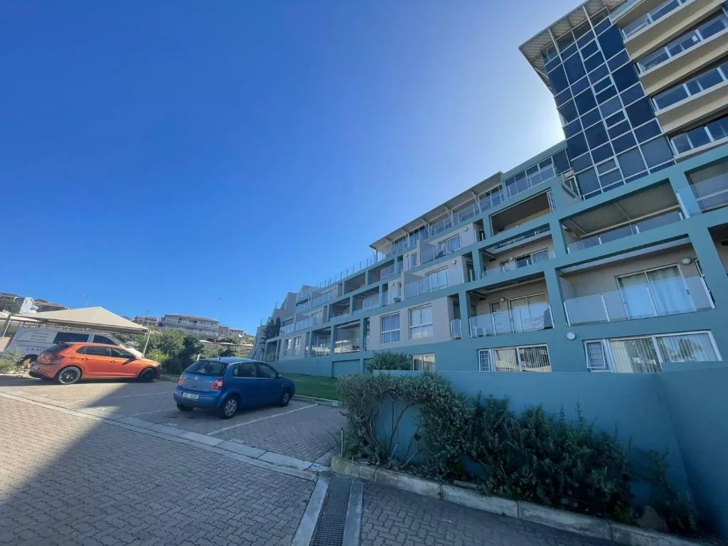 Modern apartment building facade with parking area and landscaping