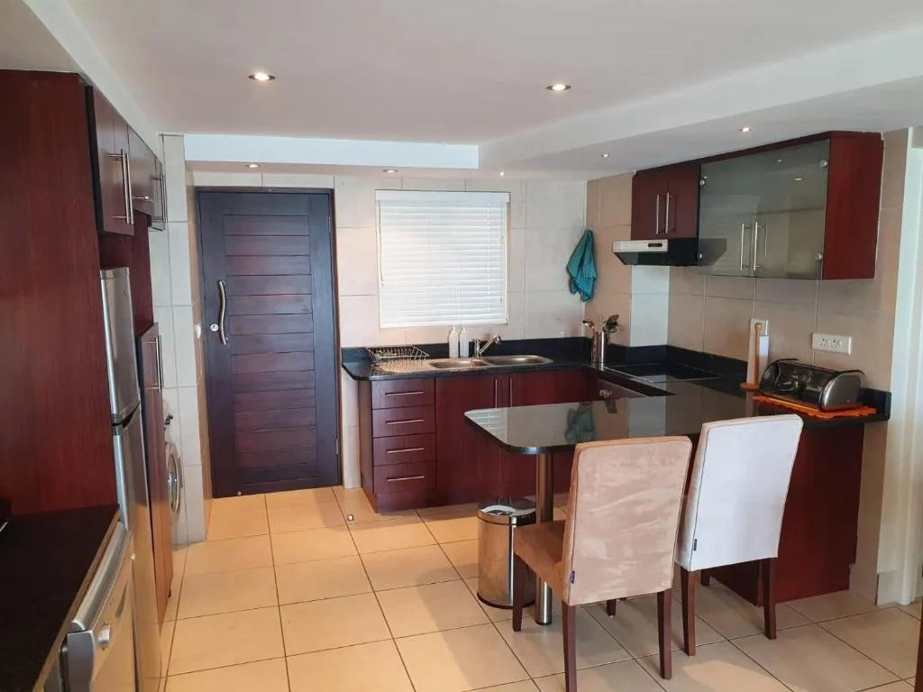Modern kitchen with burgundy cabinetry, black countertops, stainless steel appliances