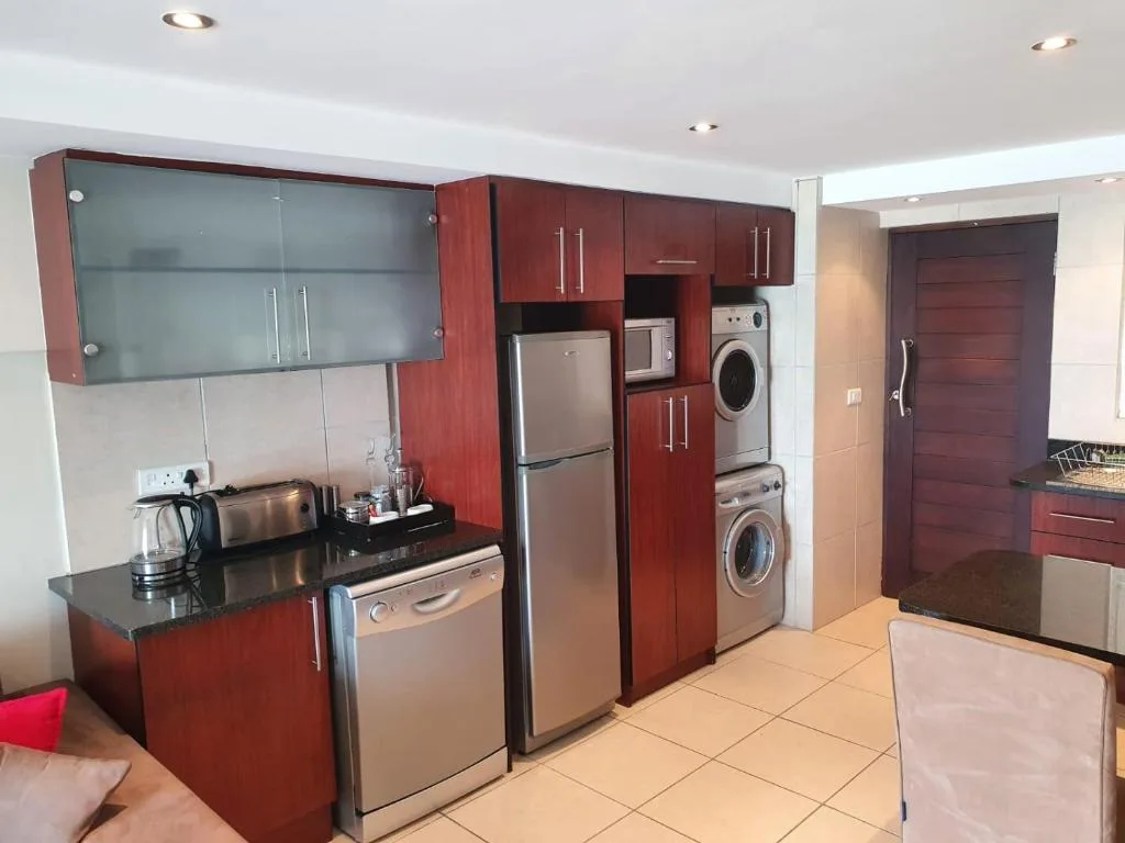 Modern kitchen with red cabinetry, stainless steel appliances, and black countertops