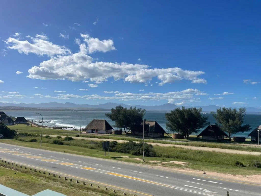Scenic coastal landscape with mountains, ocean, and traditional thatched-roof houses