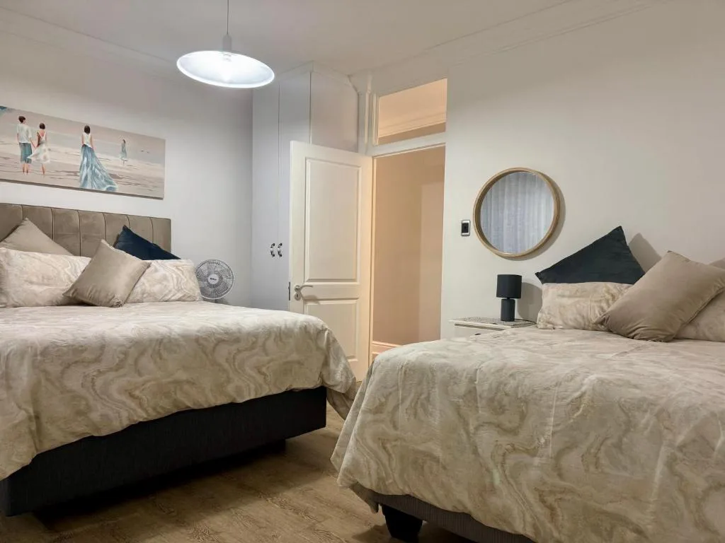 Bright bedroom with two queen beds, neutral bedding, and modern fixtures