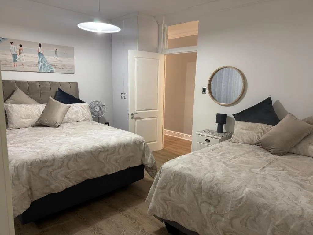 Bright bedroom with two beds, modern furnishings, and neutral tones