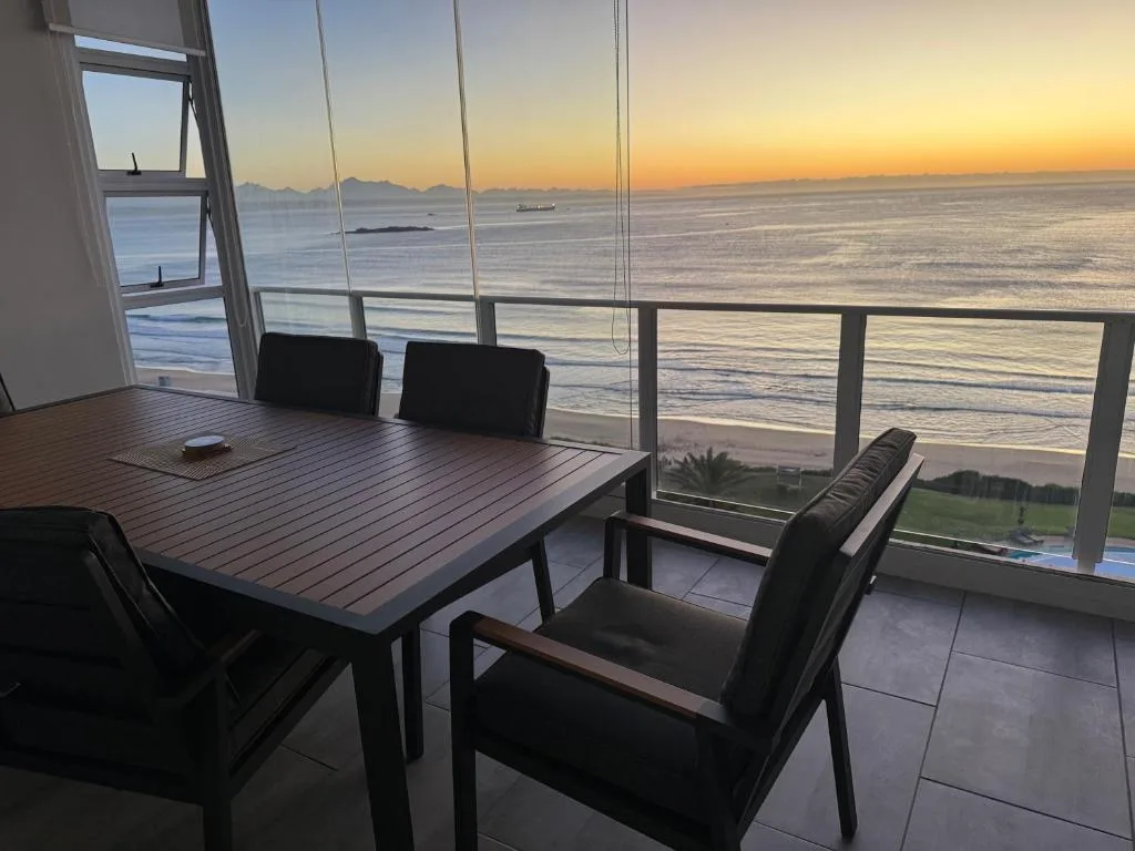 Oceanfront deck with dining table overlooking sunset and beach