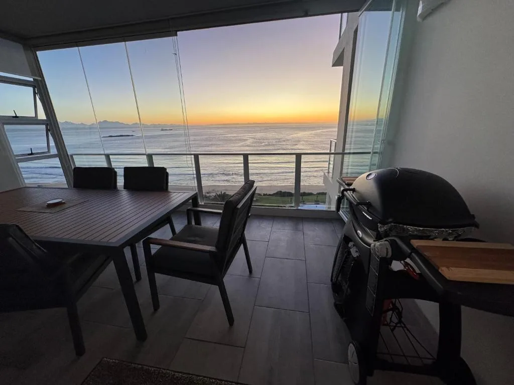 Sunset ocean view from beachfront deck with dining table and braai