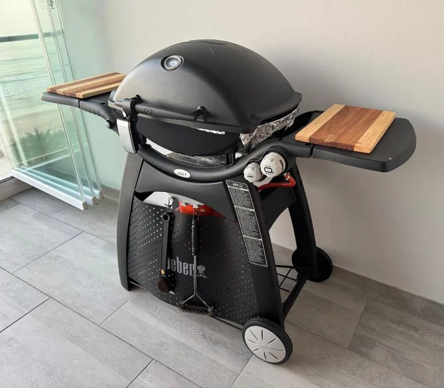 Modern black Weber gas braai grill with wooden side tables indoors