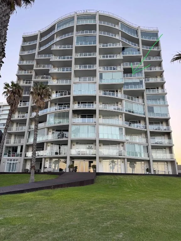 Modern curved apartment building facade with multiple balconies and palm trees