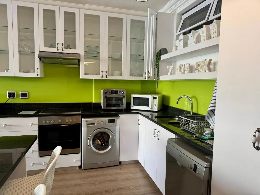 Modern kitchen with lime green backsplash, white cabinetry, and stainless appliances