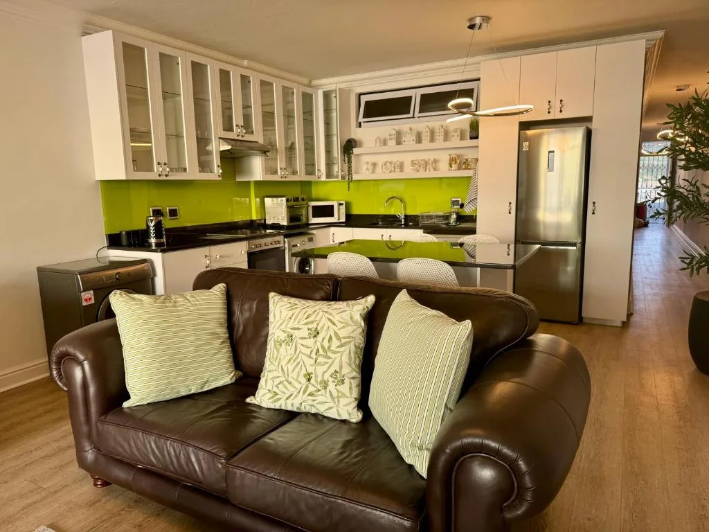 Open-plan lounge with brown leather sofa and lime green kitchen beyond